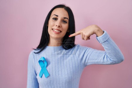 Téléchargez les photos : Femme hispanique portant un ruban bleu pointant du doigt un sourire heureux et fier - en image libre de droit
