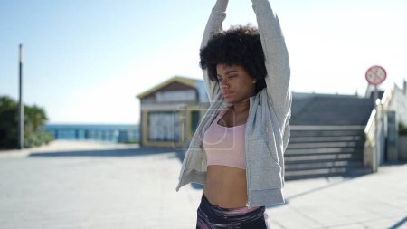 Photo for African american woman wearing sportswear stretching arms at street - Royalty Free Image