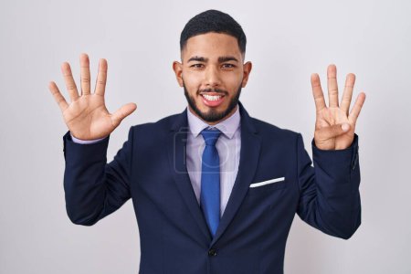 Foto de Joven hombre hispano vistiendo traje de negocios y corbata mostrando y señalando con los dedos número nueve mientras sonríe confiado y feliz. - Imagen libre de derechos