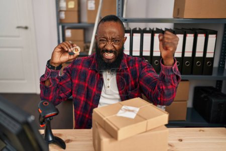 Photo for African american man working at small business ecommerce holding bitcoin annoyed and frustrated shouting with anger, yelling crazy with anger and hand raised - Royalty Free Image
