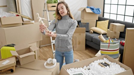 Photo for Young caucasian woman unpacking cardboard box at new home - Royalty Free Image