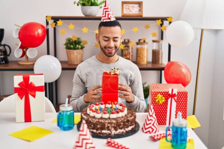 Foto de Hombre afroamericano sosteniendo regalo celebrando cumpleaños en casa - Imagen libre de derechos