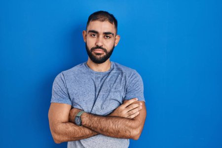 Photo for Middle east man with beard standing over blue background looking sleepy and tired, exhausted for fatigue and hangover, lazy eyes in the morning. - Royalty Free Image