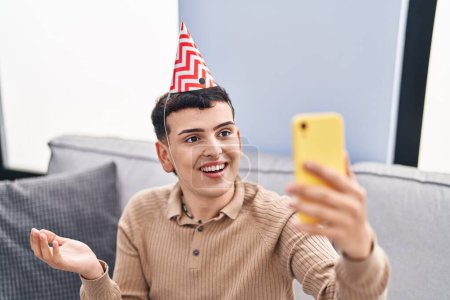 Foto de Persona no binaria celebrando cumpleaños haciendo videollamada celebrando logro con sonrisa feliz y expresión ganadora con la mano levantada - Imagen libre de derechos