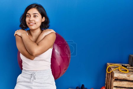 Photo for Young latin woman smiling confident training using fit ball at sport center - Royalty Free Image