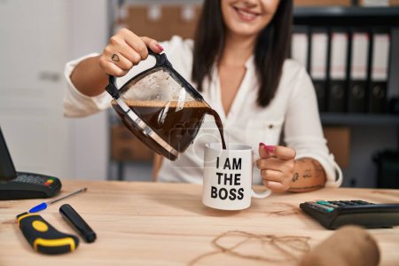Téléchargez les photos : Jeune belle hispanique femme commerce électronique travailleur d'affaires verser du café sur la tasse au bureau - en image libre de droit
