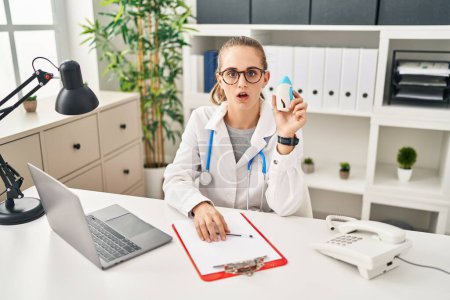 Photo for Young doctor woman wearing uniform and stethoscope scared and amazed with open mouth for surprise, disbelief face - Royalty Free Image