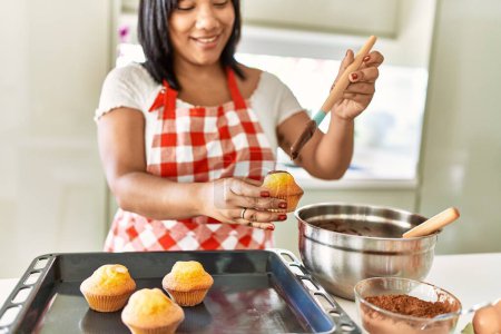 Photo for Hispanic brunette woman preparing chocolate muffins at the kitchen - Royalty Free Image