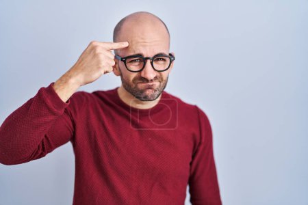 Photo for Young bald man with beard standing over white background wearing glasses pointing unhappy to pimple on forehead, ugly infection of blackhead. acne and skin problem - Royalty Free Image