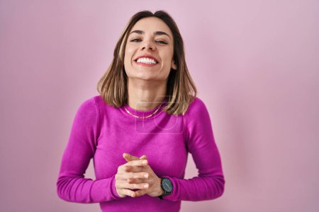 Photo for Hispanic woman standing over pink background hands together and fingers crossed smiling relaxed and cheerful. success and optimistic - Royalty Free Image