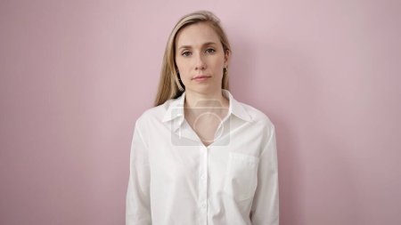 Photo for Young blonde woman standing with serious expression over isolated pink background - Royalty Free Image