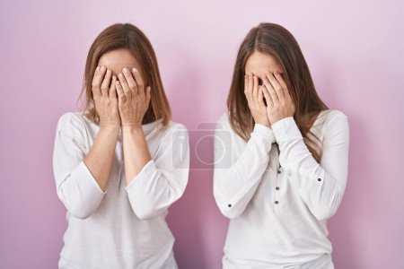 Photo for Middle age mother and young daughter standing over pink background with sad expression covering face with hands while crying. depression concept. - Royalty Free Image