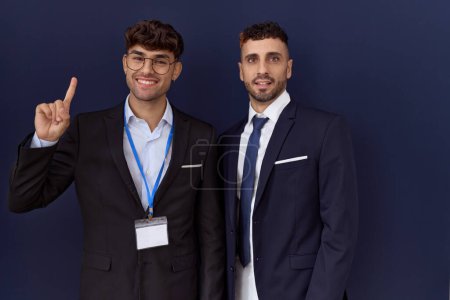 Photo for Two hispanic business men wearing business clothes showing and pointing up with finger number one while smiling confident and happy. - Royalty Free Image