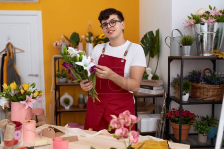 Téléchargez les photos : Homme non binaire fleuriste tenant bouquet de fleurs à la boutique de fleurs - en image libre de droit