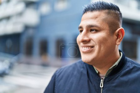 Foto de Joven latino sonriendo confiado mirando a un lado en la calle - Imagen libre de derechos
