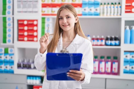 Photo for Young caucasian woman pharmacist writing on document at pharmacy - Royalty Free Image