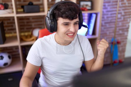 Téléchargez les photos : Non binary man streamer playing video game with winner expression at gaming room - en image libre de droit