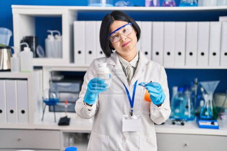 Photo for Young asian woman working at scientist laboratory relaxed with serious expression on face. simple and natural looking at the camera. - Royalty Free Image