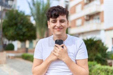 Photo for Non binary man smiling confident using smartphone at park - Royalty Free Image