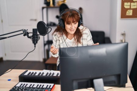 Téléchargez les photos : Middle age woman musician smiling confident having video call at music studio - en image libre de droit