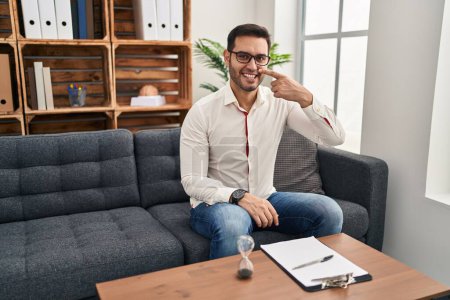 Photo for Young hispanic man with beard working at consultation office pointing with hand finger to face and nose, smiling cheerful. beauty concept - Royalty Free Image