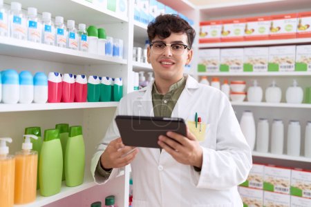 Téléchargez les photos : Non binary man pharmacist using touchpad working at pharmacy - en image libre de droit