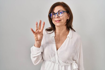 Téléchargez les photos : Middle age hispanic woman standing over isolated background showing and pointing up with fingers number three while smiling confident and happy. - en image libre de droit