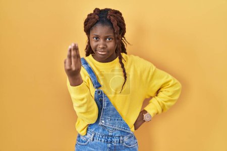 Téléchargez les photos : Femme africaine debout sur fond jaune faisant geste italien avec la main et les doigts expression confiante - en image libre de droit