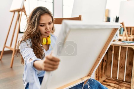 Téléchargez les photos : Young beautiful hispanic woman artist looking draw with serious expression at art studio - en image libre de droit