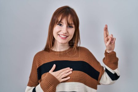 Photo for Young beautiful woman wearing striped sweater over isolated background smiling swearing with hand on chest and fingers up, making a loyalty promise oath - Royalty Free Image