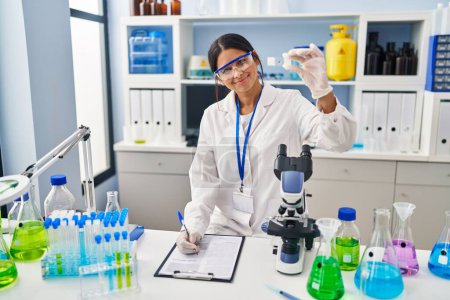 Photo for Young latin woman wearing scientist uniform working at laboratory - Royalty Free Image