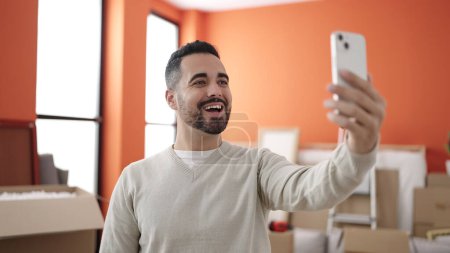 Photo for Young hispanic man having video call standing at new home - Royalty Free Image