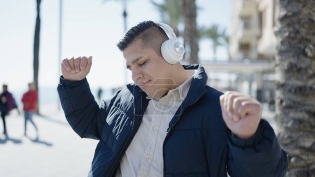 Foto de Joven hispano escuchando música y bailando en la playa - Imagen libre de derechos