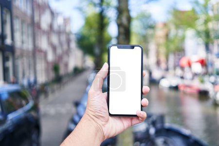 Photo for Man holding smartphone showing white blank screen at amsterdam - Royalty Free Image