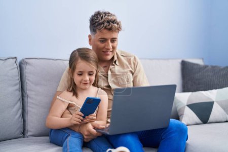 Téléchargez les photos : Père et fille père et fille utilisant ordinateur portable et smartphone à la maison - en image libre de droit