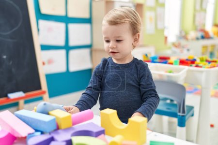 Photo for Adorable blond toddler playing with geometry blocks standing at kindergarten - Royalty Free Image