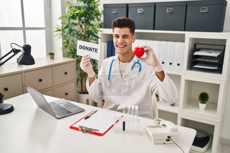 Photo for Young hispanic doctor man supporting organs donations winking looking at the camera with sexy expression, cheerful and happy face. - Royalty Free Image