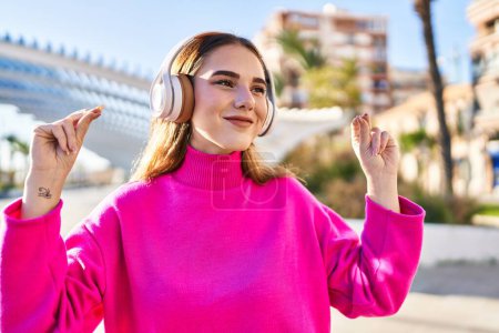 Téléchargez les photos : Jeune femme souriante confiante écoutant de la musique et dansant au parc - en image libre de droit