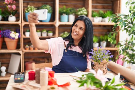 Photo for Middle age hispanic woman florist make selfie by smartphone at florist - Royalty Free Image