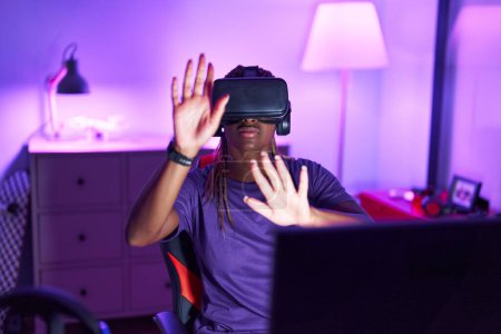 Téléchargez les photos : African american woman streamer jouer à un jeu vidéo en utilisant des lunettes de réalité virtuelle à la salle de jeux - en image libre de droit
