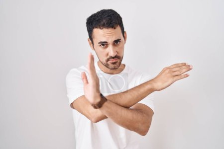 Foto de Hombre hispano guapo de pie sobre fondo blanco expresión de rechazo cruzando brazos haciendo signo negativo, cara enojada - Imagen libre de derechos
