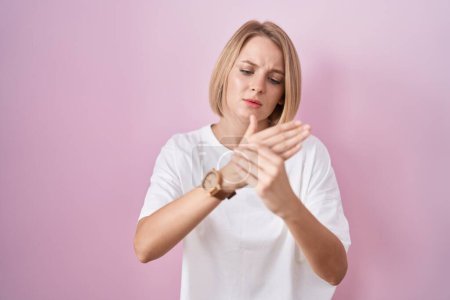 Téléchargez les photos : Young caucasian woman standing over pink background suffering pain on hands and fingers, arthritis inflammation - en image libre de droit