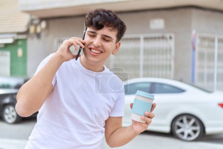 Photo for Non binary man talking on smartphone drinking coffee at street - Royalty Free Image