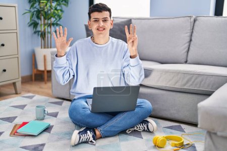 Photo for Non binary person studying using computer laptop sitting on the floor showing and pointing up with fingers number eight while smiling confident and happy. - Royalty Free Image