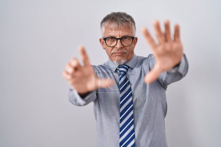 Téléchargez les photos : Homme d'affaires hispanique avec des cheveux gris portant des lunettes faisant cadre à l'aide de mains paumes et doigts, perspective de la caméra - en image libre de droit