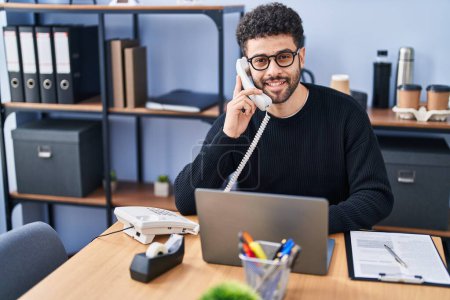 Téléchargez les photos : Jeune homme arabe travailleur d'affaires parlant au téléphone travaillant au bureau - en image libre de droit