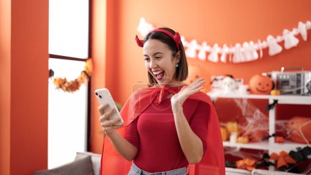 Téléchargez les photos : Jeune belle femme hispanique portant costume diable ayant appel vidéo à la maison - en image libre de droit