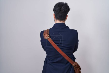 Foto de Hombre hispano con barba vistiendo ropa de negocios de pie mirando hacia atrás con los brazos cruzados - Imagen libre de derechos