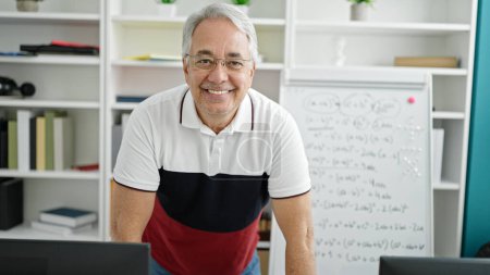 Photo for Middle age man with grey hair teaching standing by white board at university classroom - Royalty Free Image