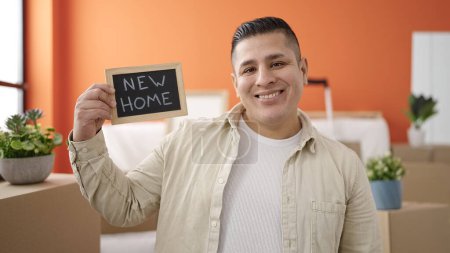 Foto de Young hispanic man smiling confident holding blackboard at new home - Imagen libre de derechos